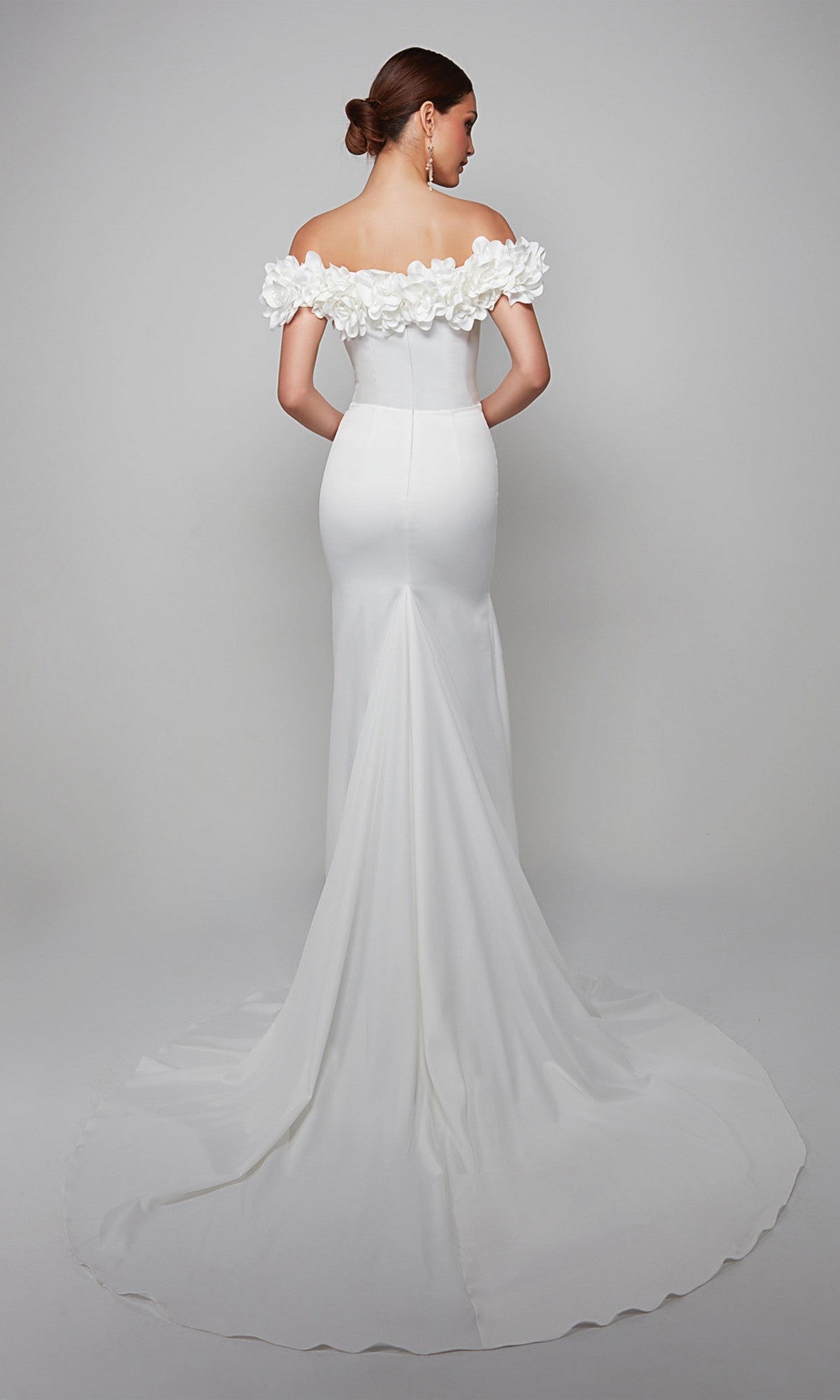 Wearing the Alyce 7061 long formal dress with off-the-shoulder floral detailing and a dramatic train, a woman stands against a plain backdrop, facing away from the camera.